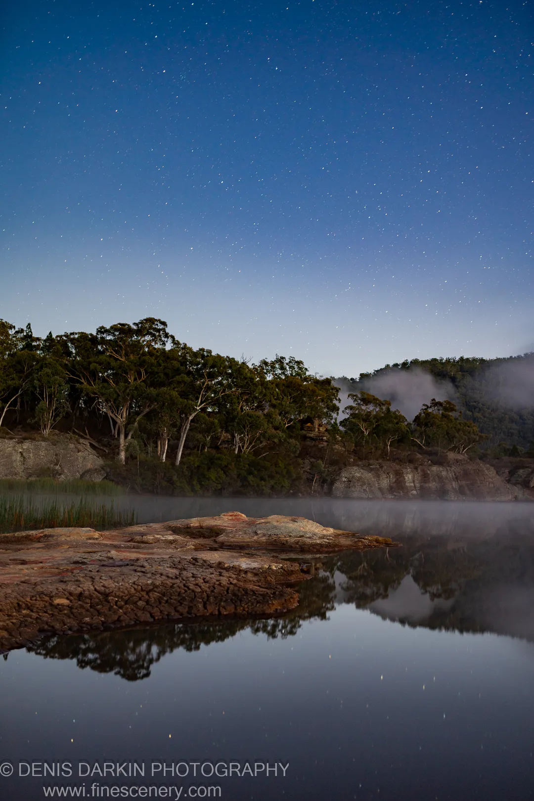 A star-flecked sky arches over Dunns Swamp at dawn, mist drifting along the banks past lichen-covered sandstone outcroppings.