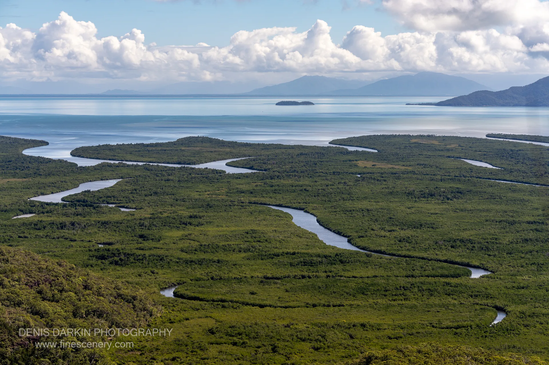 View from Nina Peak over tidal creeks coiling through mangrove flats toward a calm channel, with mainland ranges fading into haze.
