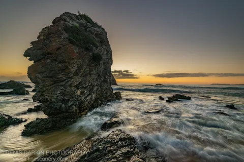 A rugged sea stack on a reef shelf at sunrise, South Coast of New South Wales, with long-exposure surf flowing around the base.