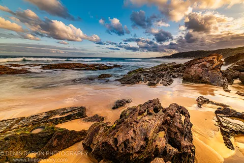 Warm dusk light on a rocky beach and tidal channel on the New South Wales South Coast, long-exposure mist around pitted volcanic rock.