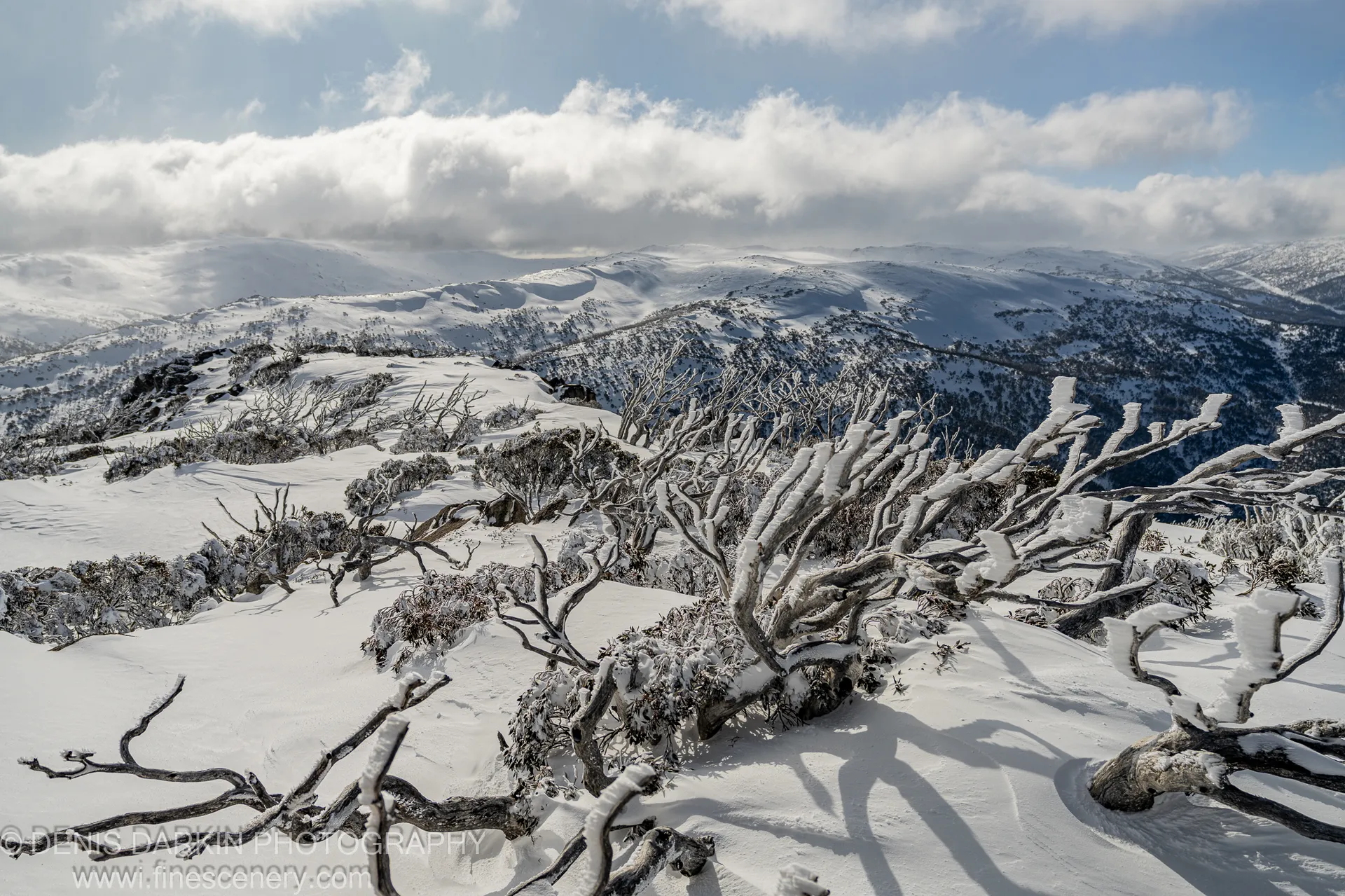 Rolling alpine ridgelines recede toward the horizon beneath a broken layer of stratus cloud over Perisher Valley, winter 2025.