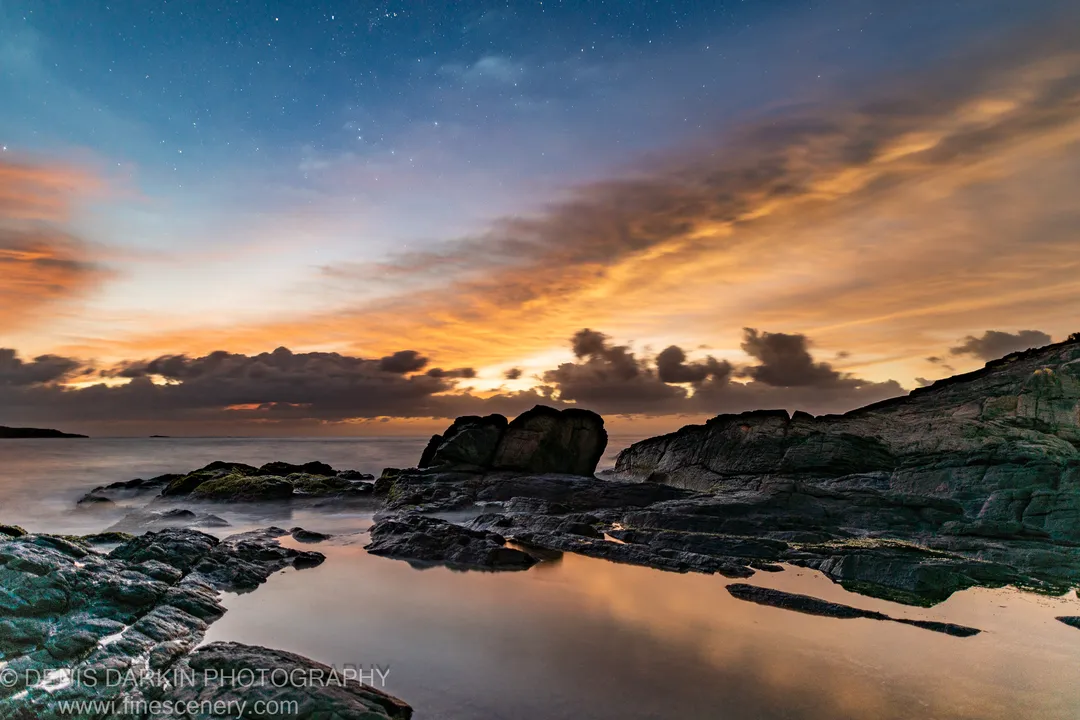 Smooth long-exposure waves on a rocky shore at pre-dawn near Nelson Bay, with moss-covered rock platforms and still tide pools in the foreground.