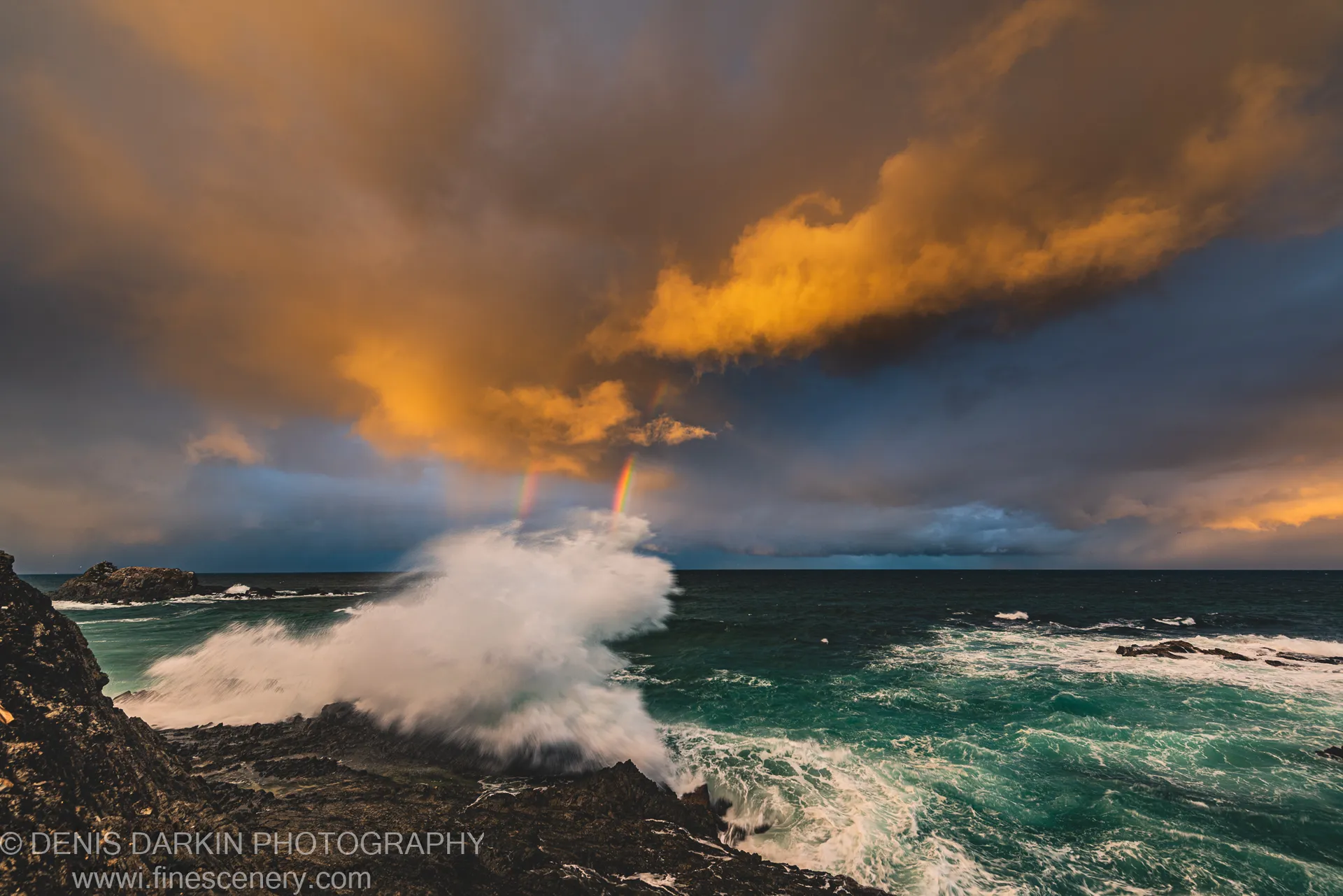 A massive wave explodes against jagged rocks at the New South Wales coast, throwing white mist into a storm-lit sky.
