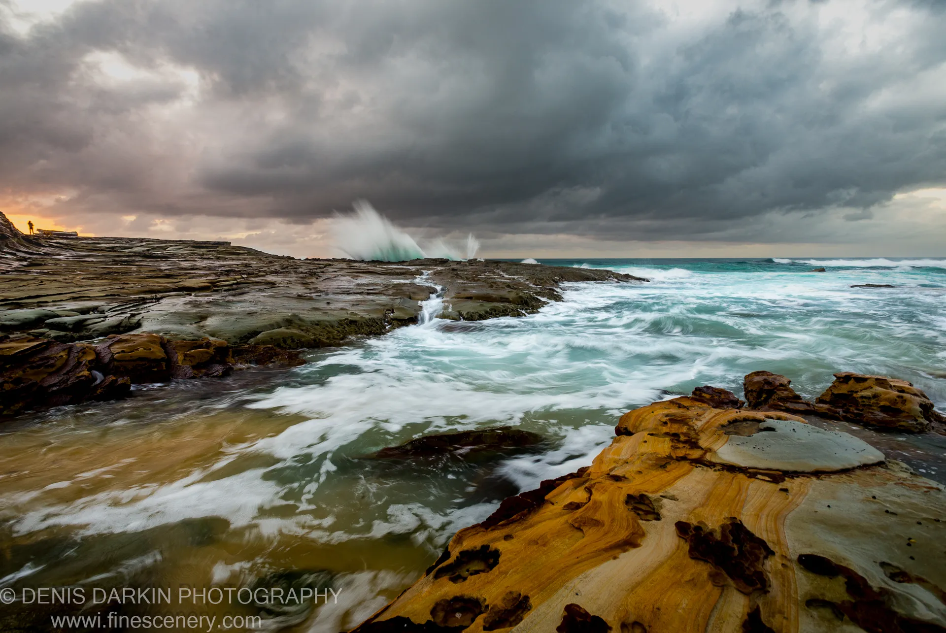 Laminated sandstone in warm tones contrasts with storm clouds and a turquoise ocean on the Spoon Bay rock platform at dawn.