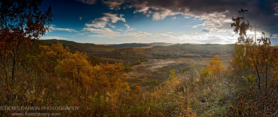 Autumn-lit valley floor and rolling hills under a deep blue sky with scattered clouds, Komissarovka River area, October 2012.