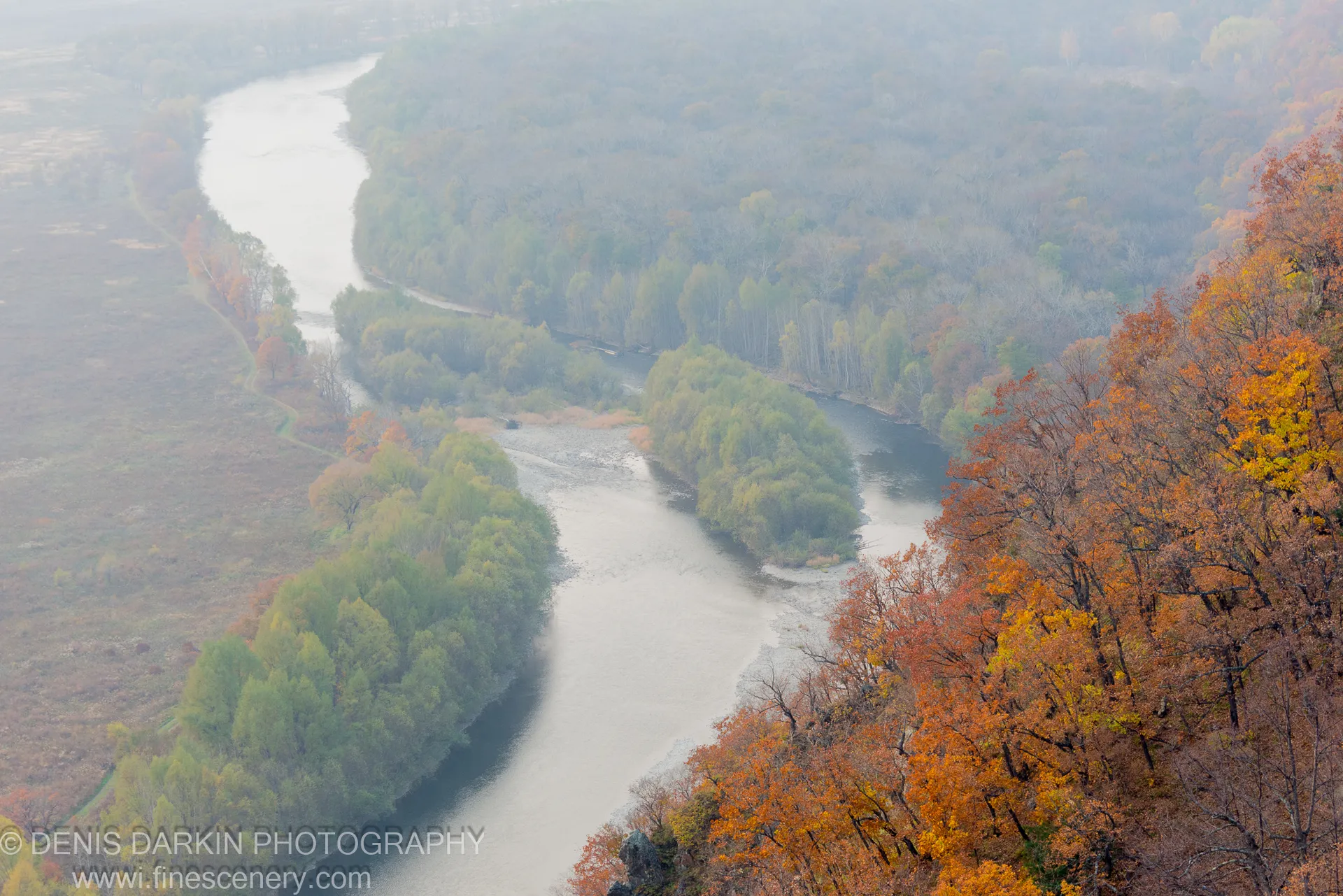A high-angle view of the pale Iman River winding through an autumn valley shrouded in morning mist, Primorsky Krai.