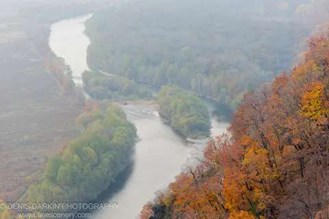 A high-angle view of the pale Iman River winding through an autumn valley shrouded in morning mist, Primorsky Krai.