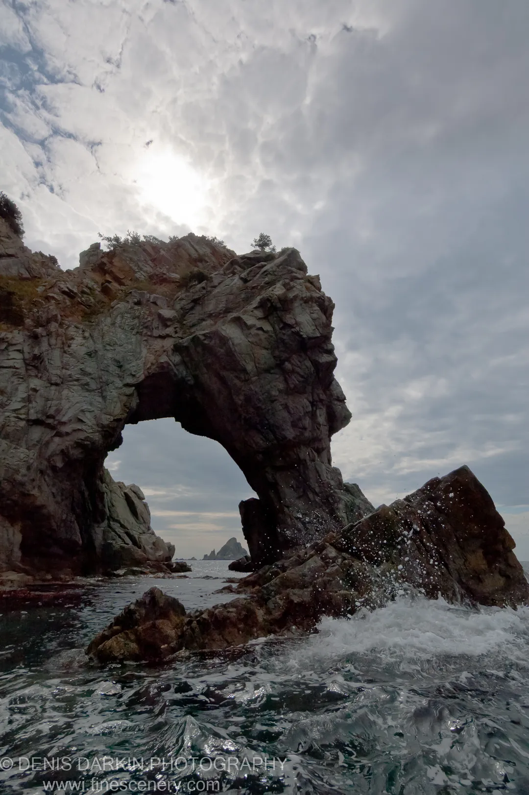 A massive weathered rock arch juts over crashing surf at Gamov Cape on the Far East Marine Reserve coast.