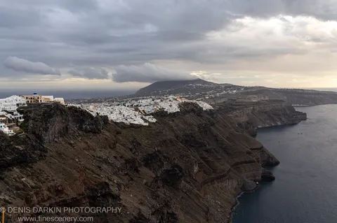 Heavy clouds hang over barren volcanic slopes and the distant caldera sea, Santorini, December 2024.